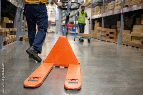 An employee is dragging a pallet truck in the warehouse.