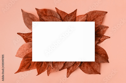 White mockup on red and orange autumn leaves on pink background. Copy space.