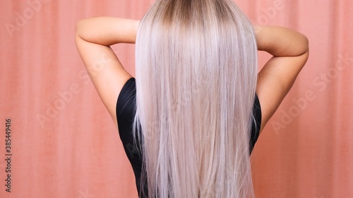 Beautiful female long straight blond hair. Dyed wavy white blond hair background, dyeing, extensions, treatment