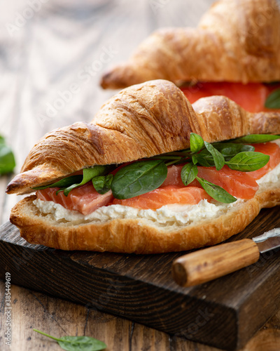 croissant with salmon, spinach and cream cheese on a wooden board, selective focus, close-up