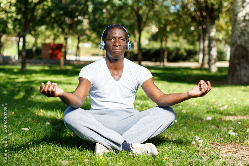 Fototapeta premium Portrait of athletic african american in headphones sitting before training in park
