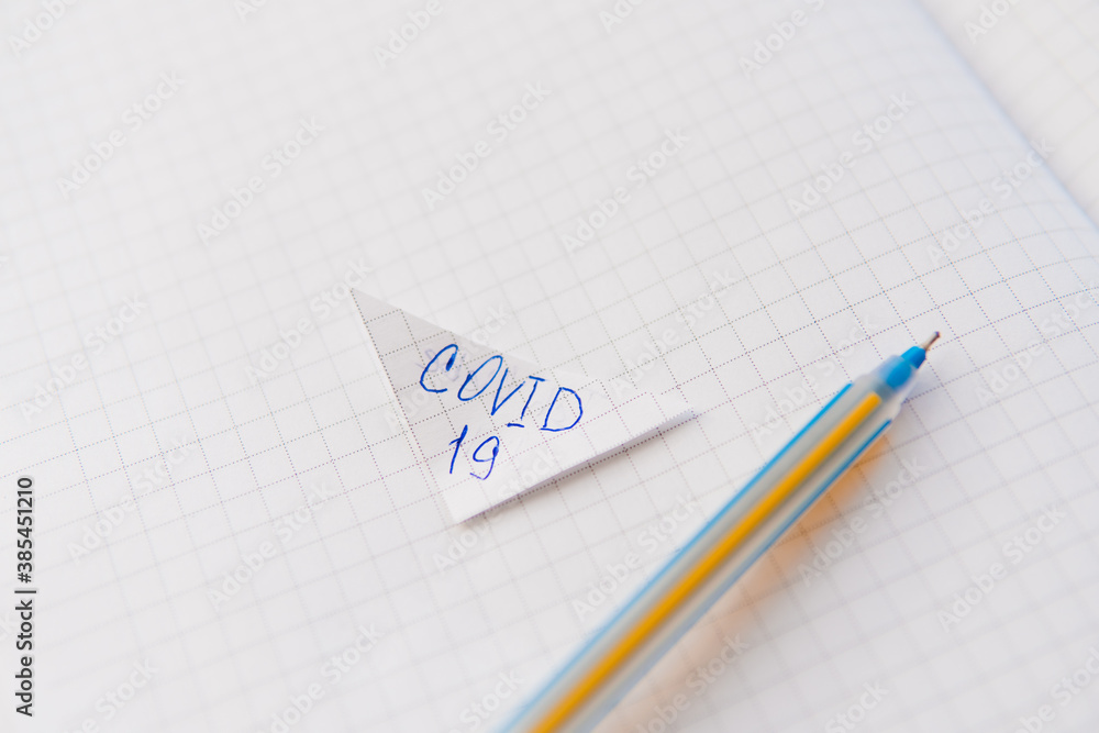 Covid-19 written on a notebook paper with pen. Covid-19 written on a notebook paper with pen.