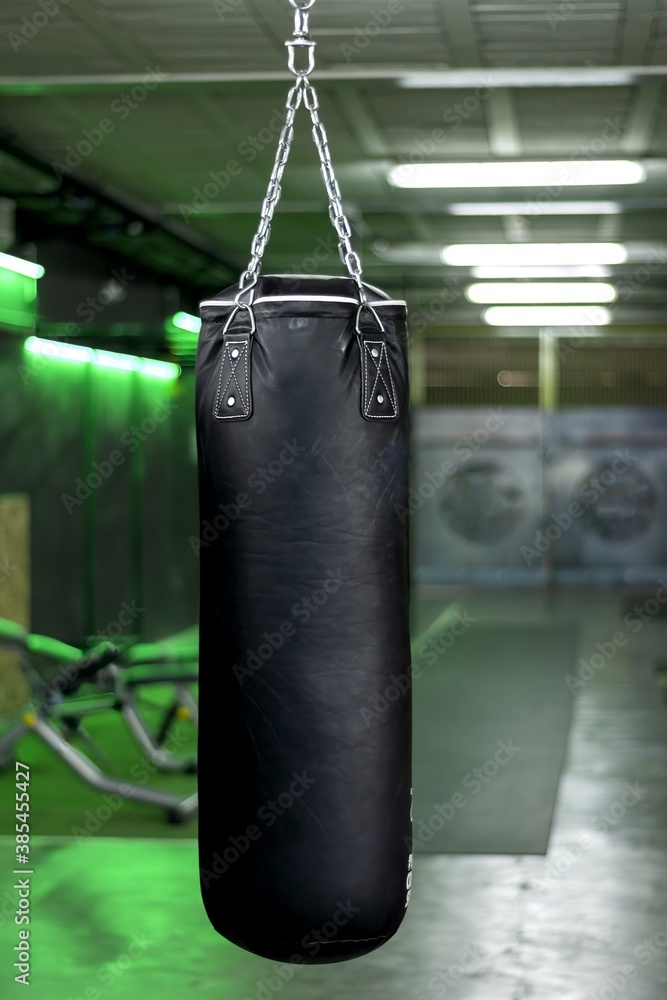 Vertical photo of a black boxing bag in a gym