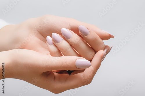 Female hands with rose nail design. Pink glitter nail polish manicure on white background