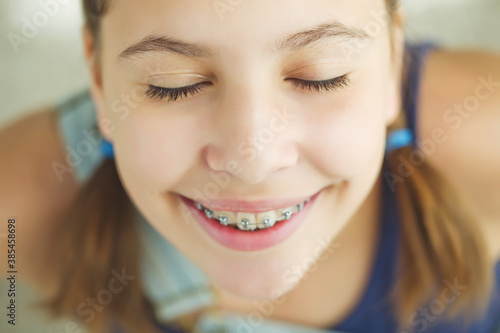 Close up portrait of smiling teenager girl showing dental braces.Isolated on white background. High quality photo.