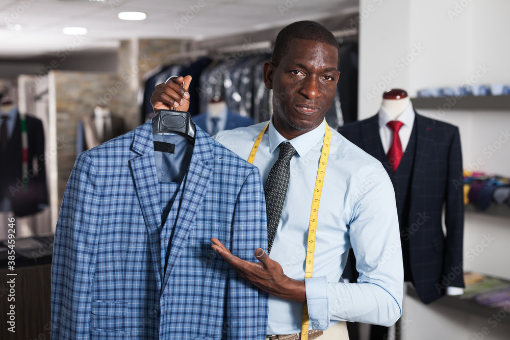 Male tailor demonstrating of fashionable suit in apparel shop. High quality photo