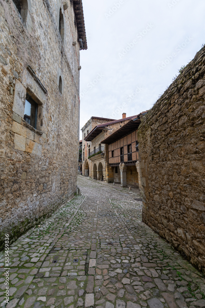 Vertical view of narrow medieval cobbled street, between stone walls in Santillana del Mar, Spain, October 1, 2020