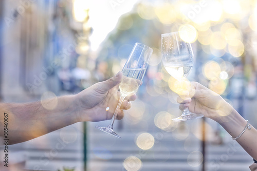 glasses of toast chin chin, hands with glasses of white wine in a street cafe
