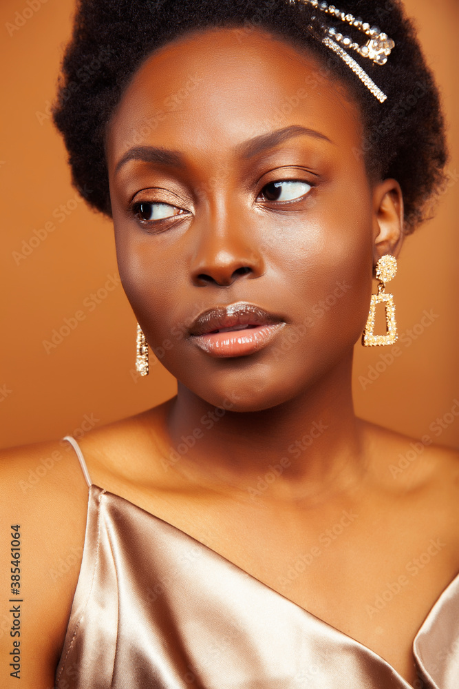 young pretty african model with golden jewelry in fashion style dress smiling happy on brown backround, lifestyle people concept young pretty african model with golden jewelry in fashion style dress smiling happy on brown backround, lifestyle people concept