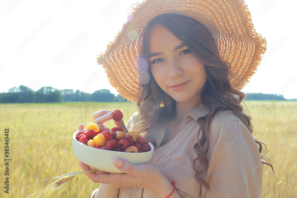 girl raspberries eating a picnic field sun / adult young model eating raspberries in a sunny summer field, enjoying happiness romance - obrazy, fototapety, plakaty 