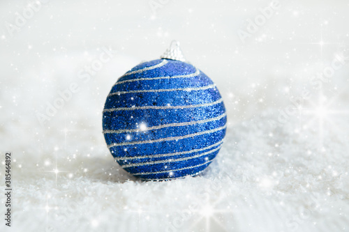 Beautiful blue Christmas ball on snow Beautiful Christmas bauble decorations lie on the white fluffy snow. Atmosphere of magic and fairy tales