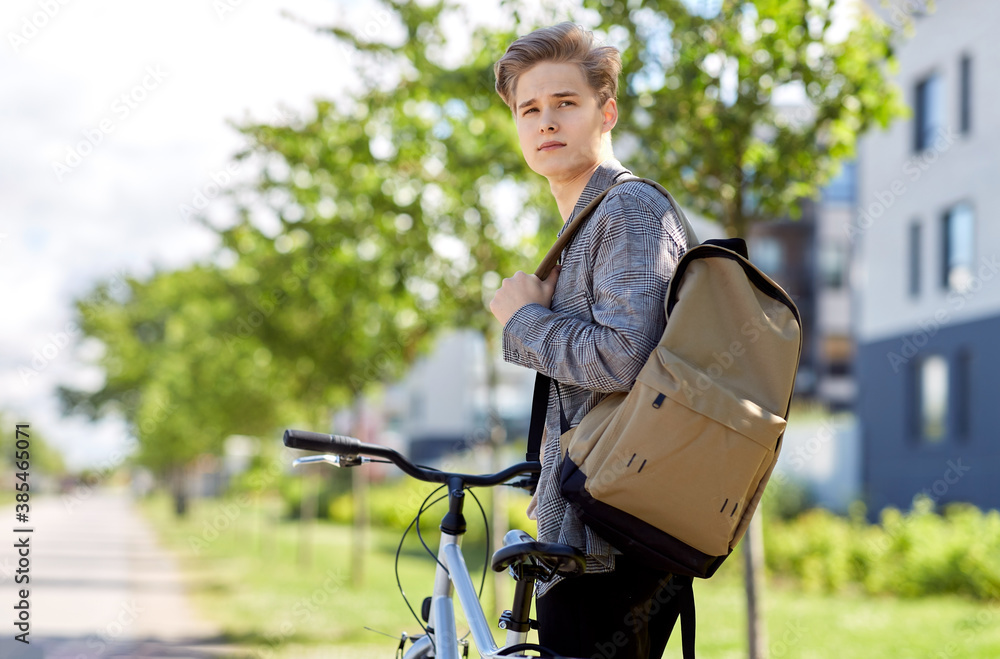lifestyle, transport and people concept - young man or teenage boy with bicycle and backpack looking back on city street