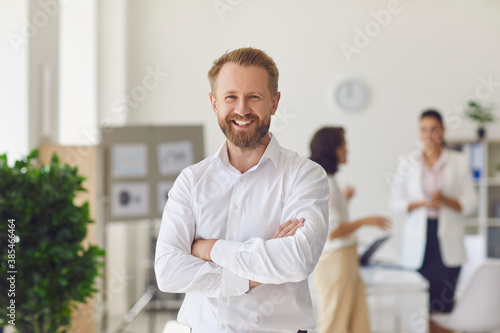 Happy successful businessman or company employee standing in office looking at camera photo