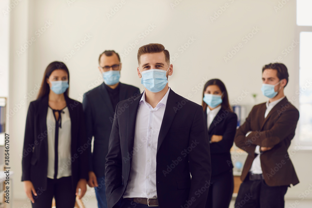 Portrait of business owner with team of employees all wearing face masks in office after reopening Portrait of business owner with team of employees all wearing face masks in office after reopening