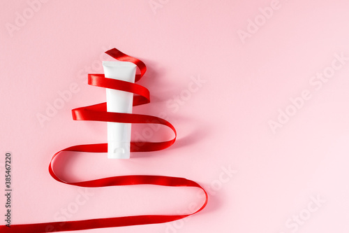 Moisturizer cream tube and red ribbon Christmas tree shape photo