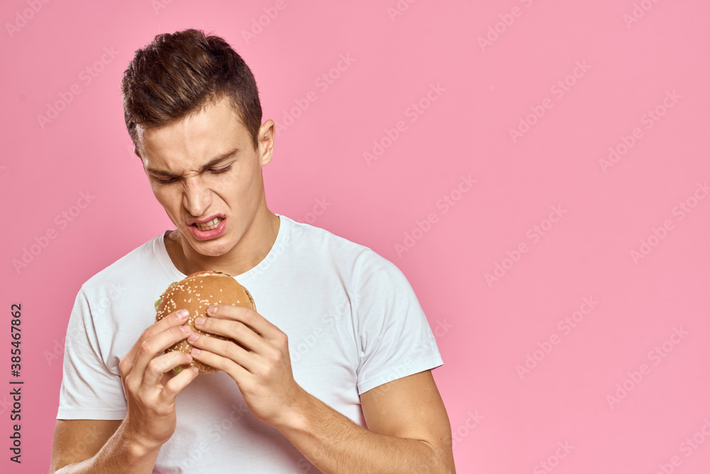 man with big hamburger on pink background calories fast food cropped view Copy Space close-up man with big hamburger on pink background calories fast food cropped view Copy Space close-up