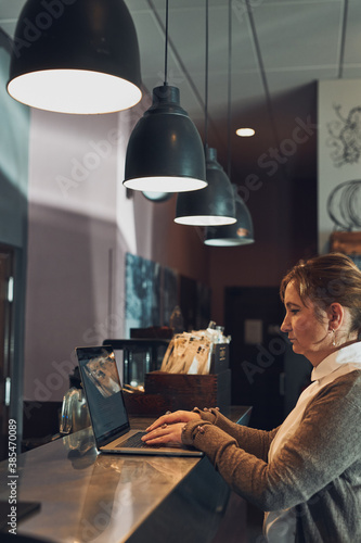 Focused businesswoman working remotely on her laptop computer contemplate managing her work sitting at the table in a cafe