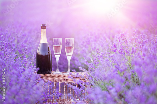 A bottle of champagne and glasses in a sunset lavender field.