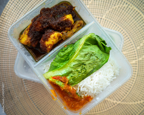 Nasi Tiga Budak Gemok or Chicken Soy sauce with grounded chillies in a take away box. Home delivery lunch. Top view. photo