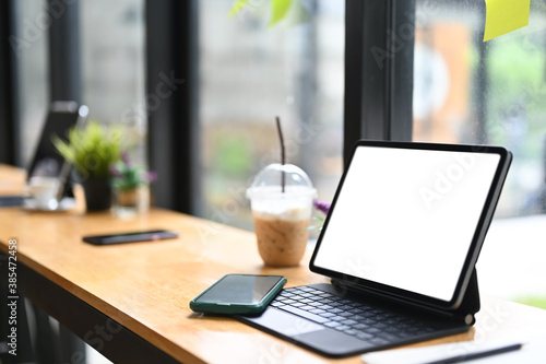 Simple workspace with blank screen tablet and coffee on wooden desk.