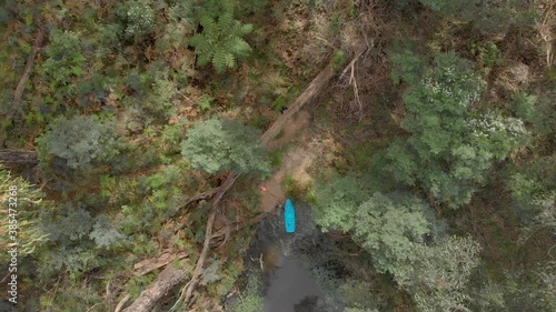 An aerial birds eye view shot of a man on a blue kayak docking his kayak into a bush gully. photo