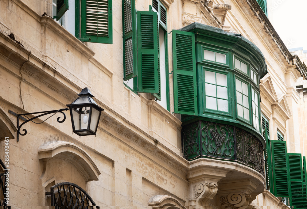 Traditional Closed Wooden Balcony With Intricate Ornate Iron Work In Valletta, Malta Traditional Closed Wooden Balcony With Intricate Ornate Iron Work In Valletta, Malta