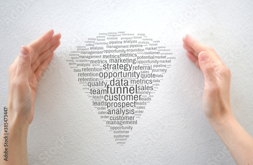 Female hands showing funnel shap'ed word cloud with sales and marketing terms