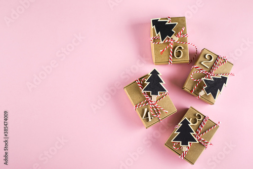 Advent christmas calendar. Wrapped gifts on pink background. Top view, flat lay photo