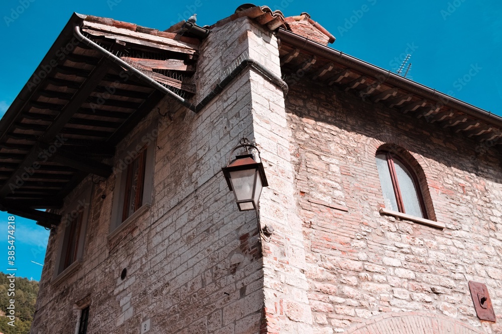 An isolated street lantern hanging on a medieval wall of an old house (Gubbio, Umbria, Italy, Europe)