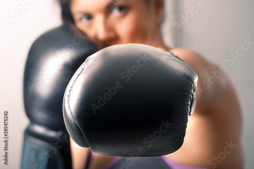 A brunette girl learns fighting techniques of self-defense in boxing gloves. © zoommachine