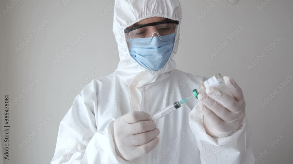 Masked gloved doctor pours coronavirus vaccine into syringe. Masked gloved doctor pours coronavirus vaccine into syringe.