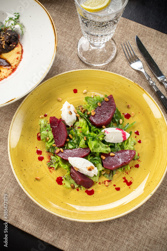 Salad with roasted beetroot, pine nuts, soft goat cheese on the table at restaurant