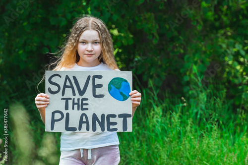 portrait of young girl standing with Save the planet Poster on school backyard. piles of plastic garbage on ground. teen kid child volunteer protest against earth pollution, global warming, recycle.