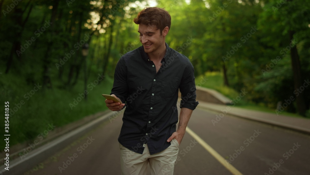 Focused man texting message outdoors. Handsome guy using smartphone in park Focused man texting message outdoors. Handsome guy using smartphone in park