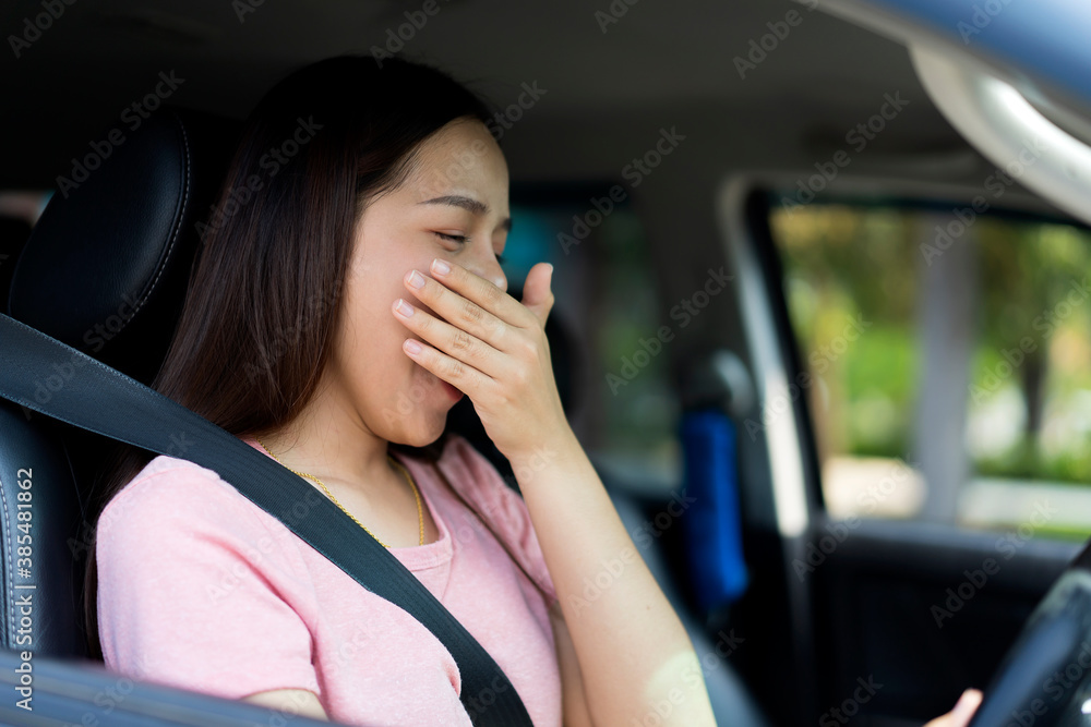 Portrait of Asian female driver yawning due to sleepy tired while riding a car, danger traffic accident insurance concept. Sleepy fatigued driver, driving car