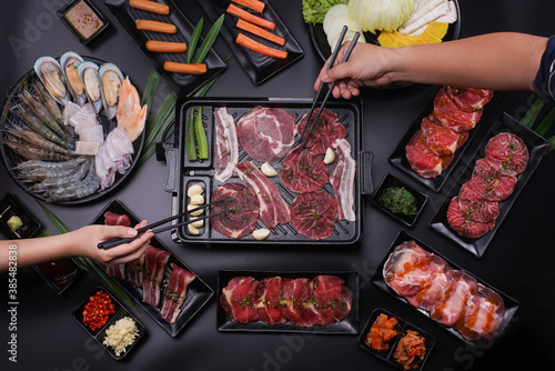 Raw beef slice for barbecue japanese style, yakiniku. Meats are being cooked on stove.