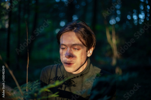 Portrait of a guy in the sunlight. Young man in nature. A student is skipping school in the woods. A guy with a regular haircut. A young man of European appearance. A man on a summer day.