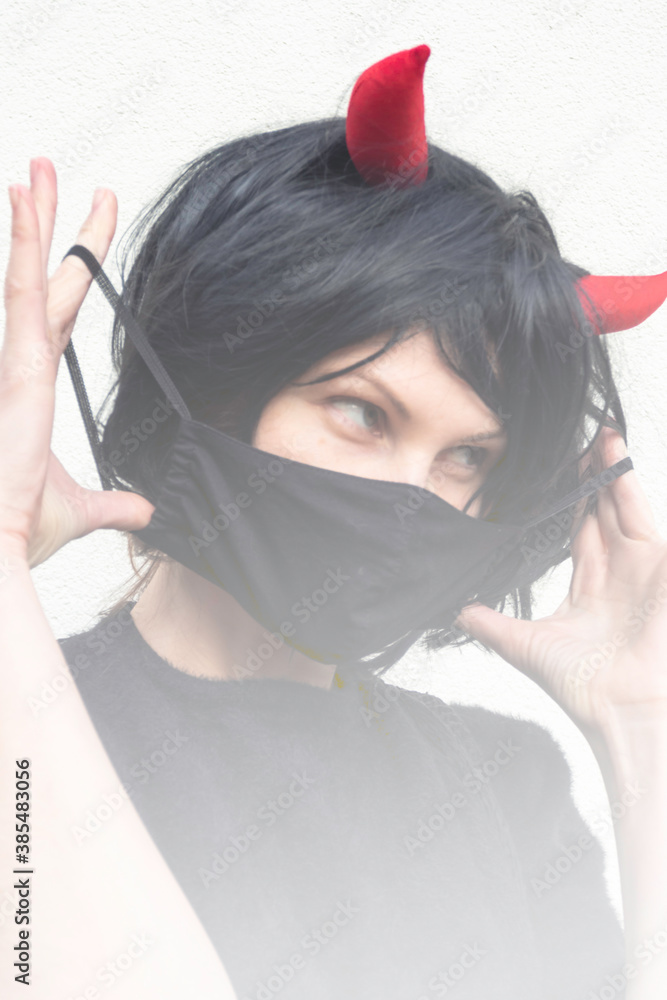 woman wearing a black medical mask and a wig with red horns