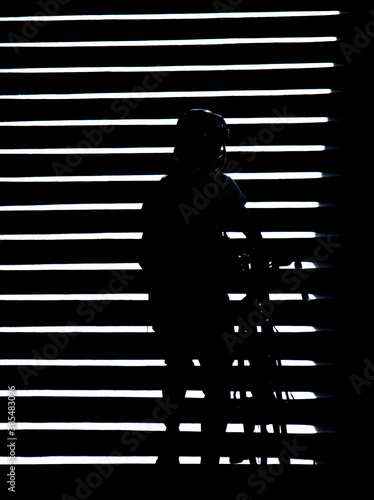 Shadow silhouette of a person pushing a bike on outdoor stairs in the night