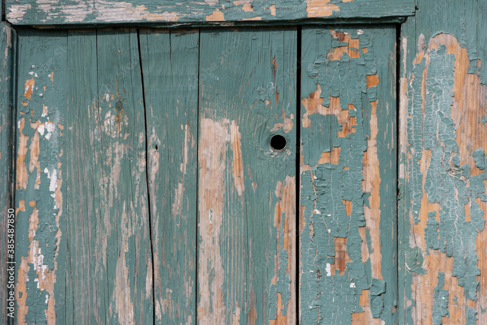 The surface of old wooden planks with peeling green paint.