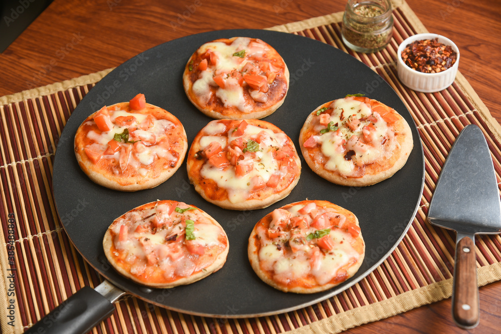 Many Mini Pizza, Fresh homemade Tawa pizzas , pan pizza cooked with  mozzarella cheese, parsley, cherry tomato and basil on rustic wooden  background . Vegetarian wheat pizza Mumbai India Stock Photo | Adobe Stock