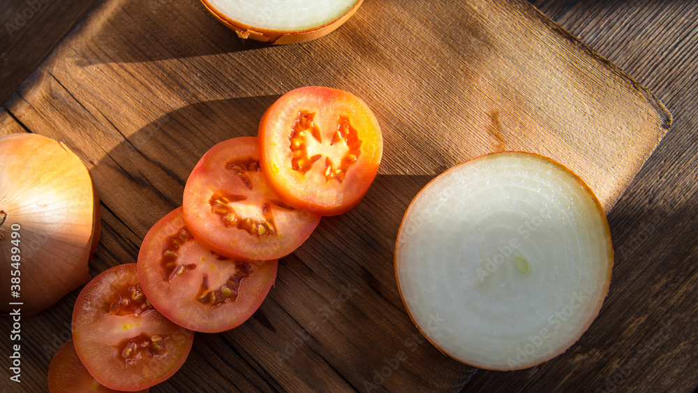 Red tomatoes,sliced tomatoes with onion slices on a dark old wooden table,close-up Red tomatoes,sliced tomatoes with onion slices on a dark old wooden table,close-up