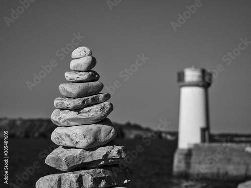 Tour de cailloux devant un phare
