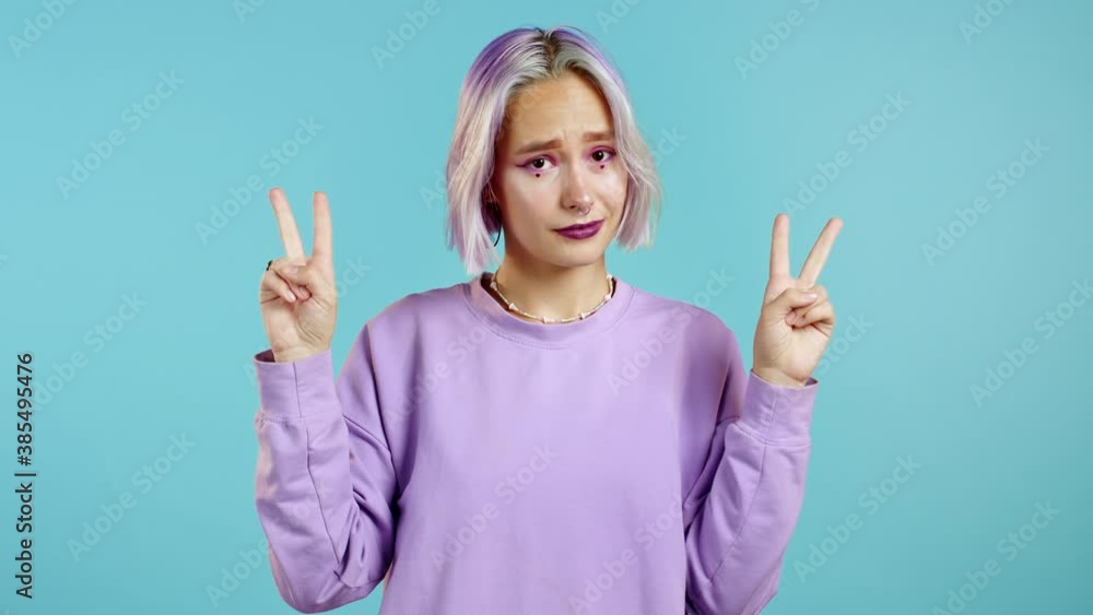Pretty hipster girl showing with hands and two fingers like quotes gesture, bend fingers isolated over blue background. Very funny, irony and sarcasm concept. Pretty hipster girl showing with hands and two fingers like quotes gesture, bend fingers isolated over blue background. Very funny, irony and sarcasm concept.