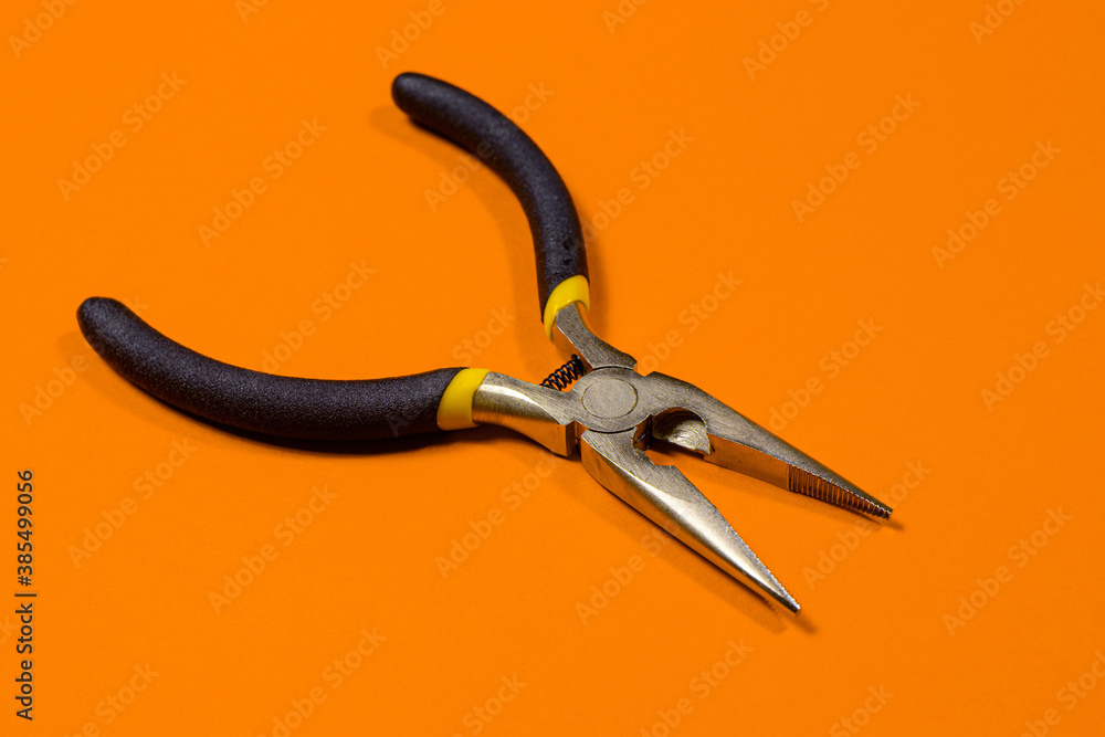 The round nose pliers on the orange background of copyspace. For electrician, jeweler and builder. Metal tool for bending wire and electrical wires The round nose pliers on the orange background of copyspace. For electrician, jeweler and builder. Metal tool for bending wire and electrical wires