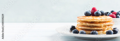 Stack of pancakes with fresh blueberries served in a dish with maple syrup. Delicious breakfast photo