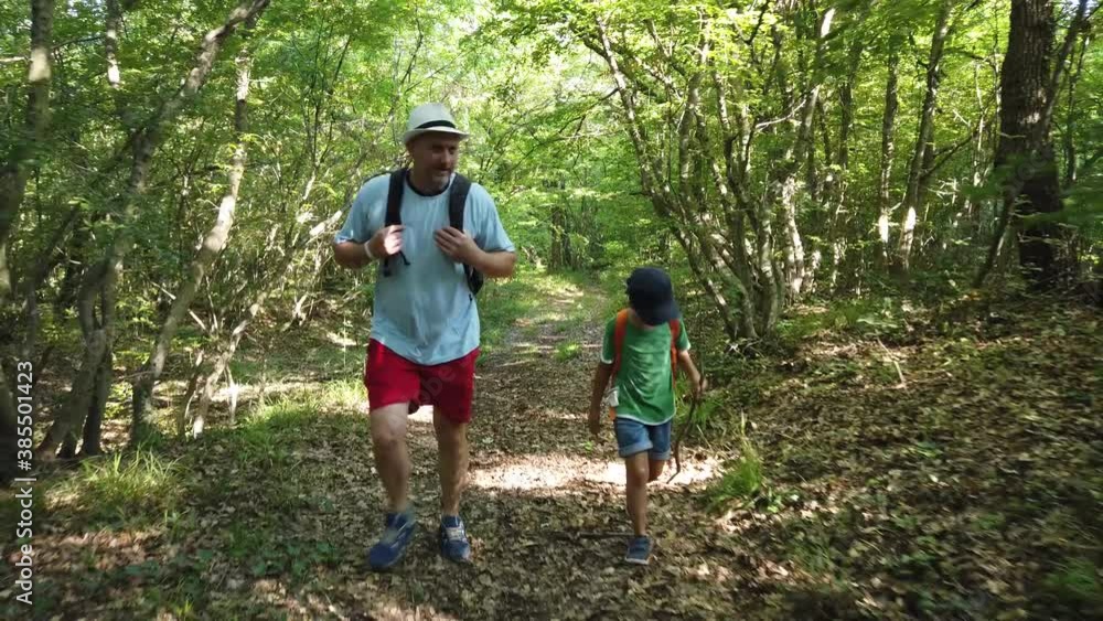 Father and son walking through the forest. Hiking in mountain with backpacks. Adventure in nature, travel lifestyle concept, active family live. Father and son walking through the forest. Hiking in mountain with backpacks. Adventure in nature, travel lifestyle concept, active family live.