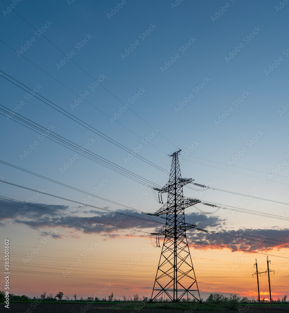 High-voltage power lines at sunset or sunrise. High voltage electric transmission tower