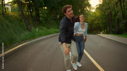 Happy man and woman having fun outdoors. Happy couple running on road in park