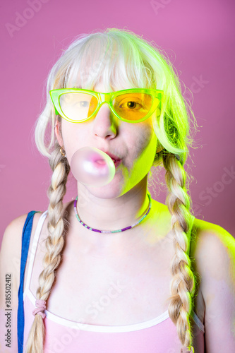 Hippy caucasian woman blowing bubble gum - Playful diverse young girl chewing gum isolated on pink background